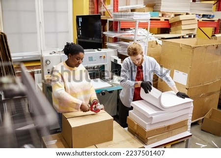 High angle view at workers opening boxes with paper in industrial print shop, copy space