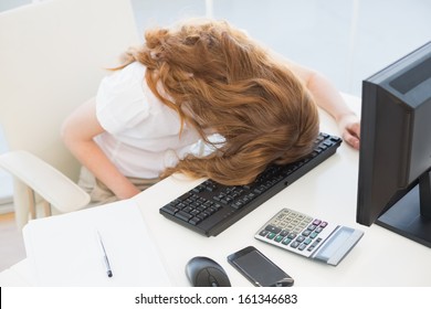 High angle view of a young businesswoman resting head on keyboard in the office