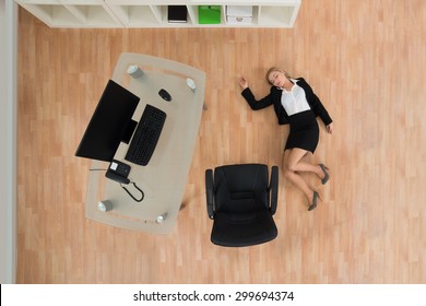 High Angle View Of Young Businesswoman Fainted On Floor In Office