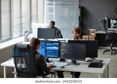 High angle view at young IT developers working with multiple computer monitors in open office copy space - Powered by Shutterstock