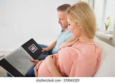 High angle view of young expecting couple looking at ultrasound scan photo