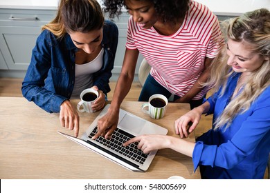 High Angle View Of Young Female Friends Using Laptop While Drinking Coffee At Home