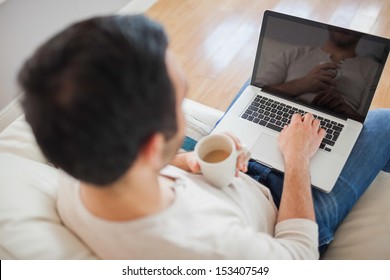 High angle view of young man using his laptop in bright living room