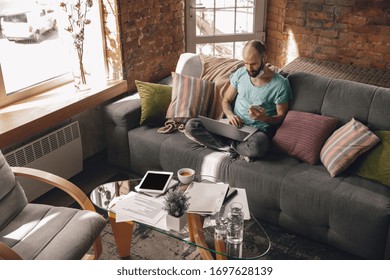 High angle view. Young man doing yoga at home while being quarantine and freelance online working. Remote office, isolated. Concept of healthy lifestyle, wellness, being safe while coronavirus