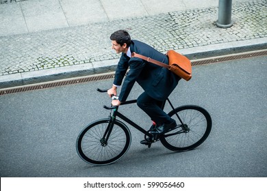 High angle view of young man wearing business suit while riding an utility bicycle on the street