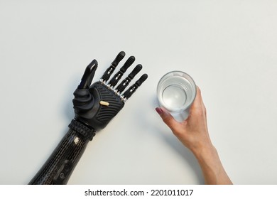 High Angle View Of Young Woman With Prosthetic Arm Holding Glass Of Water And Drinking Pill