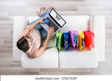 High Angle View Of Young Woman Shopping Online With Credit Card On Laptop