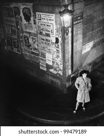 High Angle View Of A Young Woman Waiting Next To A Lantern On A Dark Street Corner