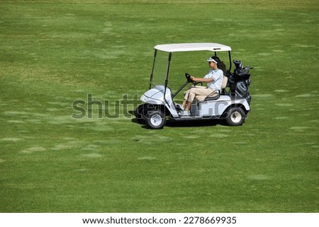 High angle view at young woman driving golf cart on green field in sunlight, copy space