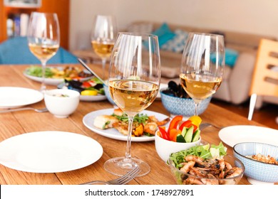 High angle of wooden table served with various homemade dishes and glasses with wine in cozy living room at home - Powered by Shutterstock