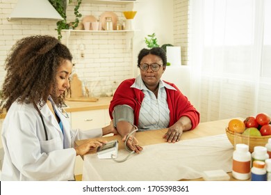 High Blood Pressure. Dark Skinned Aged Woman Being Visited By A Doctor While Having High Blood Pressure
