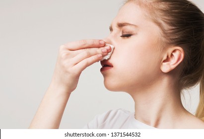 High blood pressure. Young woman suffering from nose bleeding, stop blood with tissue, free space