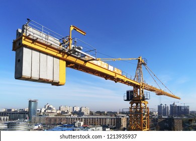 High building construction site. Big industrial tower crane with blue sky amd cityscape on background. Concrete plates weight balance. Counterweight. Aerial drone view. Metropolis city development.