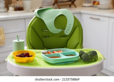 High Chair With Food In Baby Tableware On Tray Indoors