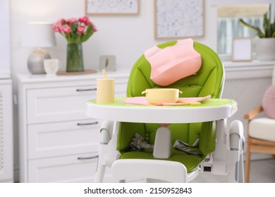 High chair with set of baby tableware on tray indoors