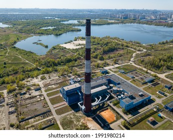 High Chimney Of A Power Plant On The Outskirts Of The City. Green Spring Steppe On The Background. Aerial Drone View.