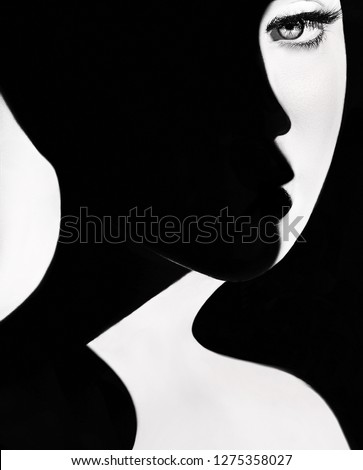High contrast black and white portrait of a beautiful girl. Girl's face with shadow. Good and evil concept. Fine art concept. Fashion portrait. Dark side person. Good and bad concept. beauty portrait