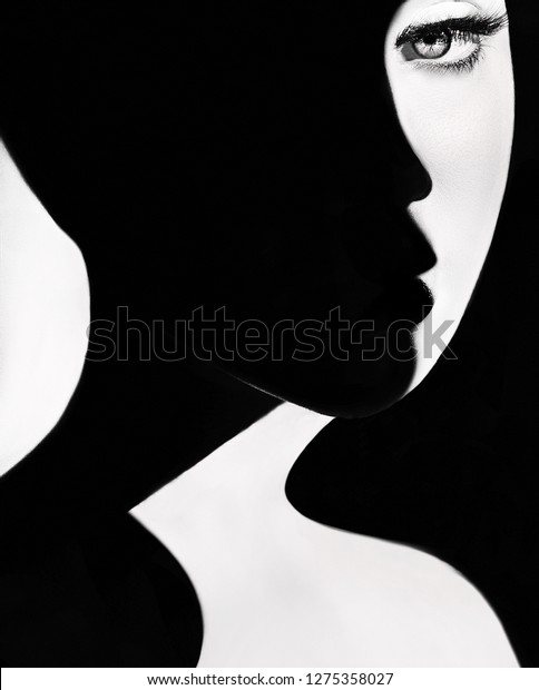 High contrast black and white portrait of a\
beautiful girl. Girl\'s face with shadow. Good and evil concept.\
Fine art concept. Fashion portrait. Dark side person. Good and bad\
concept. beauty portrait