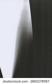 A high contrast composition split between a bright white area on the left and a deep near black zone on the right. A soft grainy gradient sweeps diagonally through the center, blending from light to dark in a smooth curved transition. Fine noise and speckling texture the midtones, giving the fade a scanned analog quality. Faint horizontal streaks and a light leak effect appear near the top edge. The stark tonal division creates a minimal abstract feel with a strong sense of light and shadow