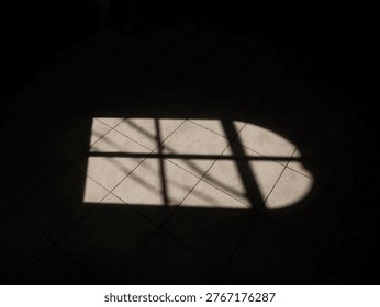 High contrast geometric light pattern falls across beige ceramic tiles creating sharp rectangular silhouette within deep black shadows illustrating minimalist architectural atmosphere