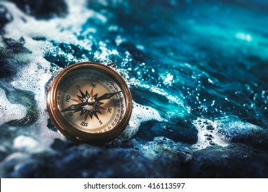 High Contrast Image Of A Compass On Rocks