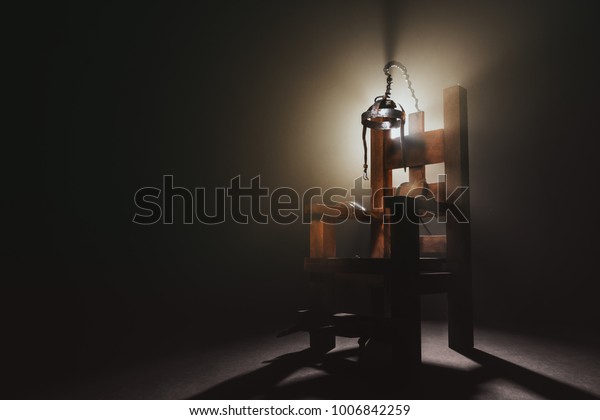 High contrast image of an electric\
chair scale model on a dark backgorund with\
smoke