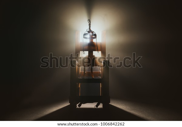 High contrast image of an electric\
chair scale model on a dark backgorund with\
smoke