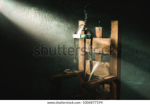 High contrast image of an\
electric chair scale model on a dark backgorund with light\
rays