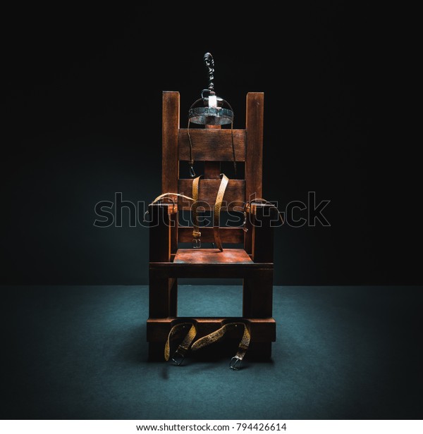 High contrast image of an electric chair scale\
model on a dark backgorund