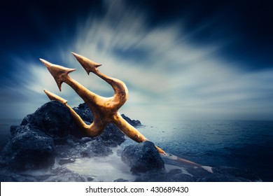 High contrast image of Poseidon's trident resting on some rocks by the sea