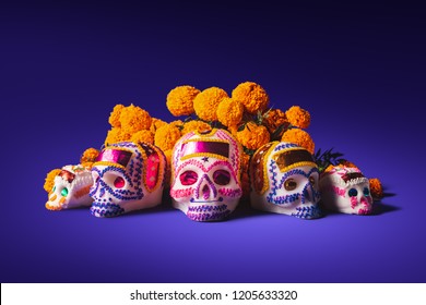 High contrast image of sugar skulls used for "dia de los muertos" celebration in a purple background with cempasuchil flowers - Powered by Shutterstock