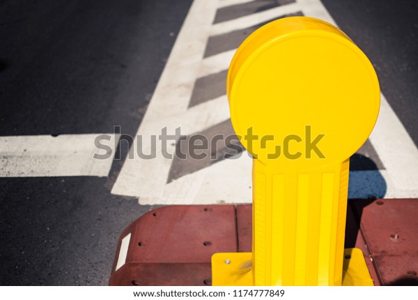 High contrast image of a yellow\
plastic road sign in the middle of the road. Katowice,\
Poland