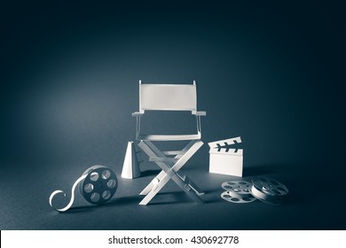 high contrast vintage image of Director chair and several movie items made from paper on a wood surface