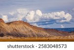 High desert hills in western Colorado.  Large cinder mountains of Grand Junction.  Blue sky and tan grass in foreground. Grand Valley cliffs in Grand Junction, Colorado.