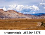 High desert hills in western Colorado.  Large cinder mountains of Grand Junction.  Blue sky and tan grass in foreground. Grand Valley cliffs in Grand Junction, Colorado.