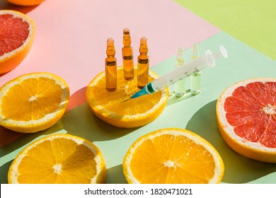 High dose vitamin C, ampule for injection with syringe and fresh juicy orange fruit slides. Concept of vitamin,mineral supplement, beauty product .Organic Natural Cosmetics Concept