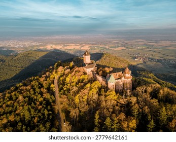 High drone view capturing castle complex, forested slopes and maplike valley patterns, long shadow play and clear topographic perspective