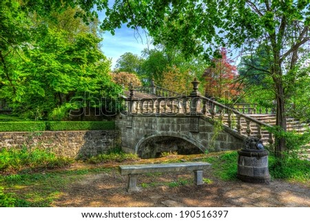 A high dynamic range painting alike picture of a small bridge over water with trees and sky in the background