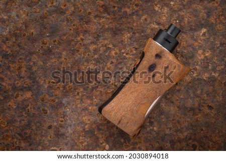high end rebuildable dripping atomizer with natural stabilized walnut wood regulated box mods on rusty texture background with copy space, vaporizer equipment
