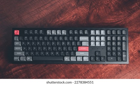 High end wireless mechanical keyboard on clean wooden desk in a dimly lit office - Shutterstock ID 2278384551