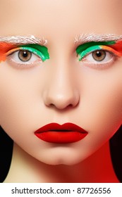 High Fashion And Beauty Portrait Photography. Beautiful Girl Model Face With Creative Bright Makeup Like A Doll, Rainbow Eyes And Red Lips Make-up