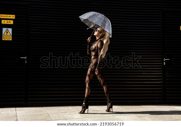 High fashion look. Glamour stylish model in black\
latex costume and and high heels on is walking in the city. Sexy\
stylish blonde woman in bodystocking lingerie is posing outdoor.\
Sexy Lingerie model.