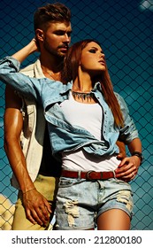 High Fashion Look.beautiful Couple Sexy Stylish Blond Young Woman Model With Bright Makeup With Perfect Sunbathed Skin And Handsome Muscled Man In Vogue Style In Jeans Outdoors Behind Blue Sky
