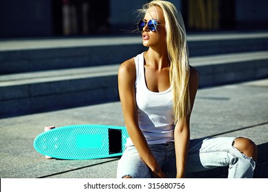 High Fashion Look.glamor Stylish Sexy Beautiful Young Blond  Model Girl In Summer Bright Casual Hipster Clothes With Skateboard Sitting In The Street