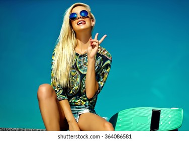 High Fashion Look.glamor Stylish Sexy Beautiful Young Cute Blond Model Girl In Summer Bright Casual Hipster Clothes With Skateboard Behind Blue Sky Showing Victory Sign