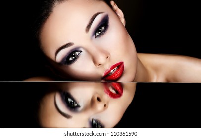 High Fashion Look.glamour Fashion Portrait Of Beautiful Sexy Brunette Girl Female Model With Bright Makeup And Red Lips And Her Reflection In Mirror Table On Dark With Perfect Skin