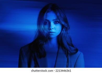 High Fashion Model Girl In Bright Neon UV Lights Posing In Studio, Portrait Of A Beautiful Woman, Trendy Retro Look, Generation Z. Blue Glow Effect.