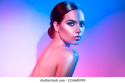 High Fashion model girl in colorful bright sparkles and neon lights posing in studio, portrait of beautiful woman, trendy glowing make-up. Art design colorful make up. Glitter Vivid neon makeup