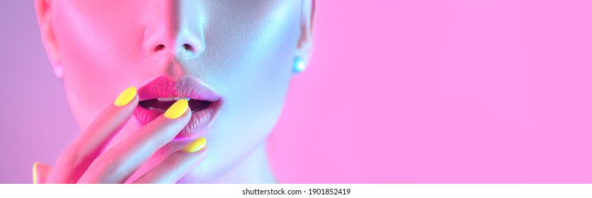 High Fashion model girl in colorful bright UV lights posing in studio, portrait of beautiful woman with trendy make-up and manicure. Art design, colorful make up. Over colourful background.
