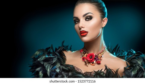 High Fashion Model Girl Portrait with Trendy gothic make-up, Black Hair style, Make up, dark accessories. Halloween Vampire Woman portrait with black smoky eyes, feathers dress, over black background